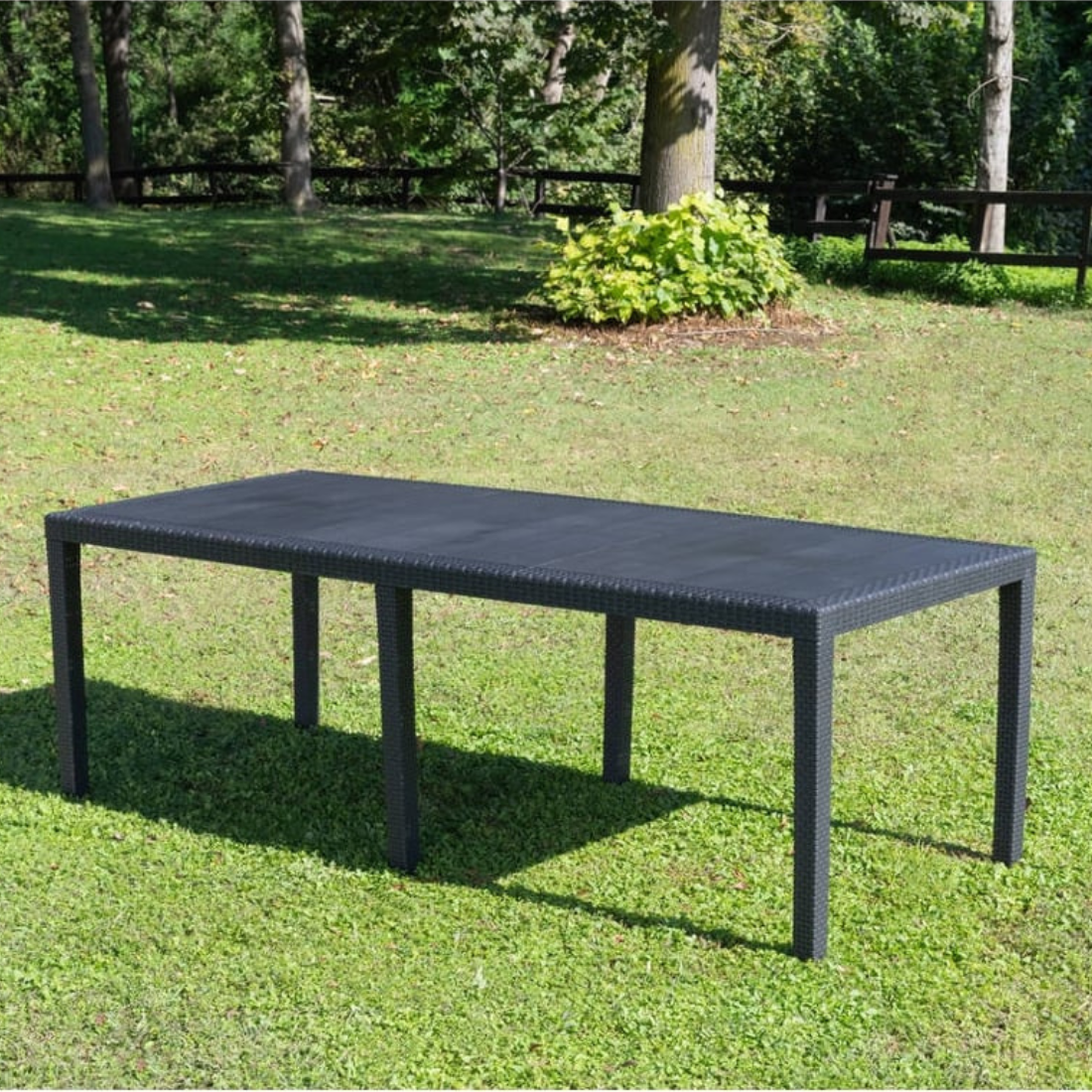 Mesa IPAE PROGARDEN em plástico, de cor cinzenta, com ranhuras e acabamento trançado e 6 pés de suporte. Exibido em ambiente exterior.