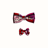 Coleira do Snoopy Zooz para animal, de padrão cor de rosa, vermelho e roxo, com imagens do personagem e um laço do mesmo padrão. Vista frontal, de vários tamanhos, sobre fundo branco