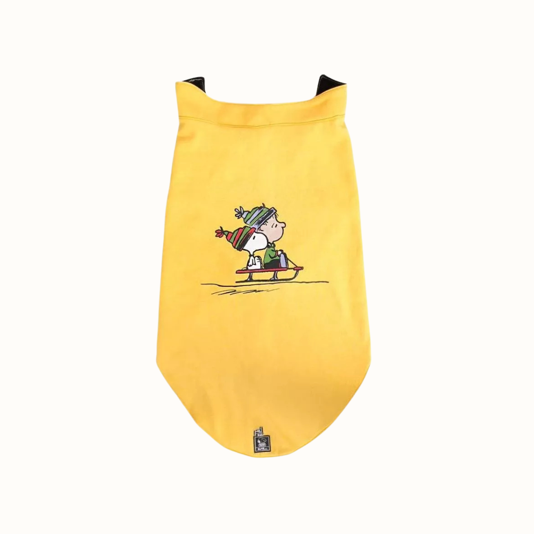 Colete Zooz para cão na cor amarela, com detalhes em preto, com estampa do  personagem a deslizar na neve com um gorro e cachecol, acompanhado do Woodstock. Vista frontal, sobre fundo branco. 